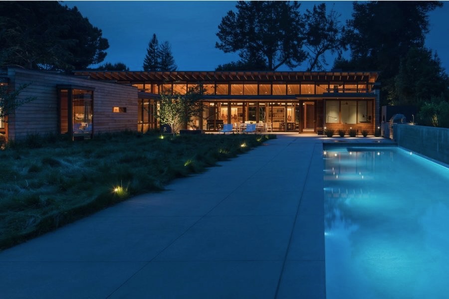 Illuminated pool and timber residence at dusk